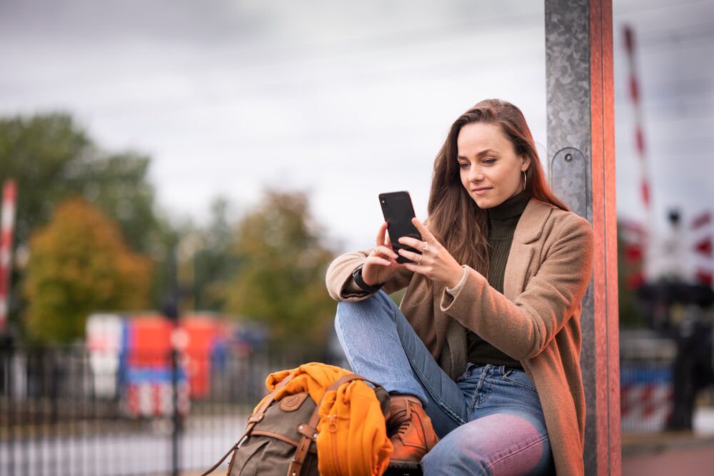 Meisje op perron kijkt op telefoon