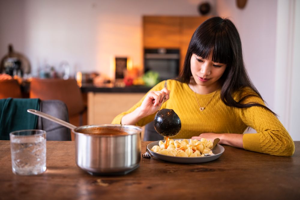 jonge vrouw pasta eten thuis